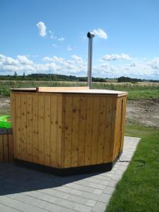 a wooden hot tub sitting on top of a field at Thorupgaard Farm Holiday in Stenum