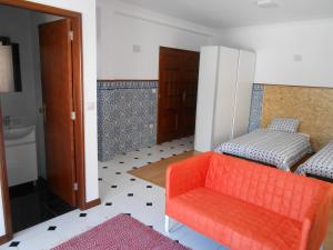 a living room with an orange chair and a bed at Sinos Rio Tinto in Campainha