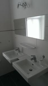 a white bathroom with two sinks and a mirror at Ûnderdak in Warns
