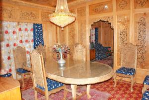 comedor con mesa, sillas y lámpara de araña en New Bul Bul Group of Houseboats Srinagar, en Srinagar