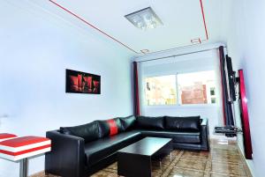 a living room with a black leather couch and a window at Appart Clim Wifi 700m de la Plage in Saïdia