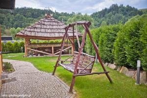 a wooden swing in a garden with a gazebo at Willa Eliza in Muszyna