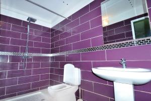 a purple tiled bathroom with a sink and a toilet at Appart Clim Wifi 700m de la Plage in Saïdia