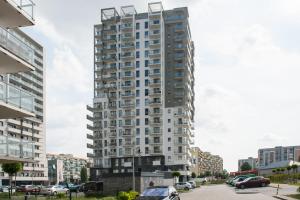 a tall building with cars parked in a parking lot at Albatross Towers Joda Bed in Gdańsk