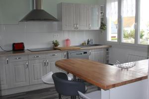 a kitchen with white cabinets and a wooden table at Appartement lumineux et Agréable 6 Personnes in Saint Malo