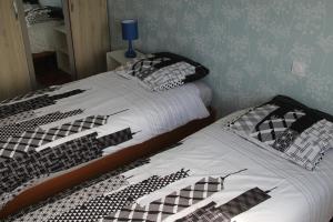 2 camas con sábanas y almohadas blancas y negras en Appartement lumineux et Agréable 6 Personnes en Saint-Malo