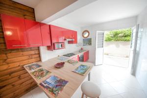 a kitchen with red cabinets and a wooden table at Residence fruit de la passion F4 in Sainte-Anne
