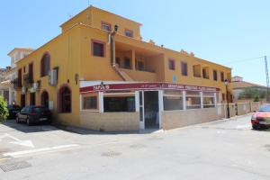 un edificio amarillo con un estacionamiento delante de él en Apartamentos Turísticos Edificio del Pino, en Sorbas