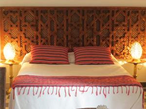 a bed with two red striped pillows on it at Riad Arous Chamel in Tangier