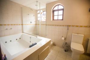 a bathroom with a tub, toilet and sink at Pousada Big Bear in Campos do Jordão