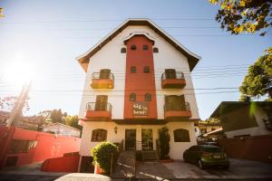 a building with a tower with a car parked in front at Pousada Big Bear in Campos do Jordão