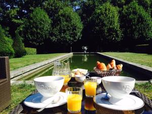 a table with a bowl of food and glasses of orange juice at Le Domaine de Cordey in Boucé