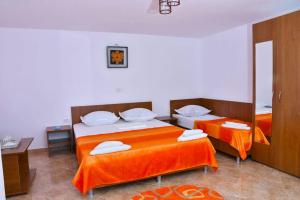 um quarto com 2 camas com lençóis laranja e um espelho em Casa Kmy em Tuzla