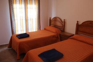 Un dormitorio con dos camas con edredones naranjas y una ventana. en Apartamentos Turísticos Edificio del Pino, en Sorbas