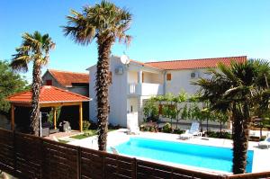 a swimming pool in front of a house with palm trees at Filipovic Apartments with Pool in Biograd na Moru