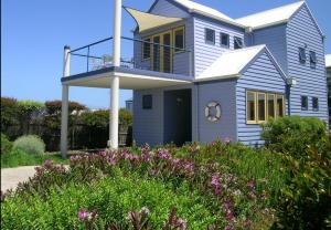 Apollo Bay的住宿－雷維爾船屋酒店，带阳台的蓝色房子,有些鲜花