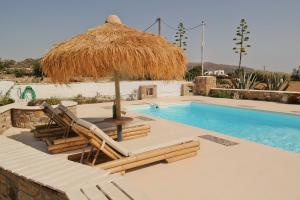 a pool with chairs and a straw umbrella and a swimming pool at Villa Mozaik in Plaka