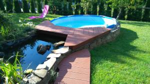 a swimming pool with a wooden walkway around it at Apartament Kapi in Kalwaria Zebrzydowska