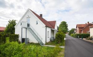 ein weißes Haus mit einer Treppe neben einer Straße in der Unterkunft Studio på loftet i Sankt Olof in Sankt Olof