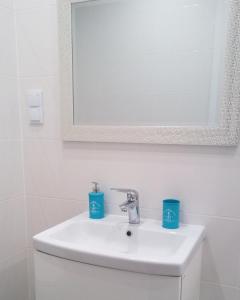 a bathroom sink with two blue cups on it at Apartament Ku Morzu II Ustronie Morskie in Ustronie Morskie