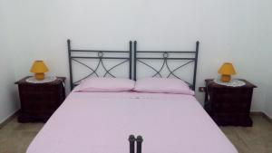 a bedroom with a bed with pink sheets and two lamps at Casa Vacanze Le Macchie in Parabita