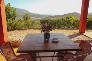 - une table en bois avec un vase de fleurs sur une terrasse couverte dans l'établissement Fighezia, à Fluminimaggiore