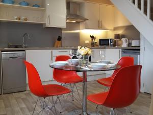 a kitchen with a table and red chairs at Pomegranate in Coleford