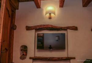 a tv on the side of a wall with a lamp at Les Bergeries "Le figuier" in Omessa