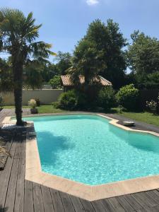 a swimming pool with a wooden deck at Les Rives du Bassin in Le Teich