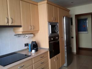 a kitchen with wooden cabinets and a stainless steel refrigerator at Casa Cafer in Las Palmas de Gran Canaria