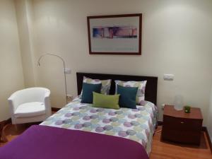 a bedroom with a bed and a white chair at Casa Cafer in Las Palmas de Gran Canaria