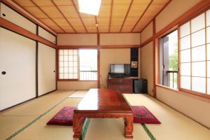 a living room with a wooden table and windows at Minshuku Fukufuji in Nikko