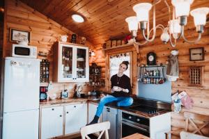 a man sitting on the counter of a kitchen at Log Cabin at White River in Kiðjaberg