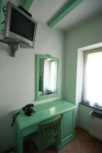 een kamer met een groen bureau met een spiegel en een televisie bij Albergo Belvedere in Borghetto di Vara