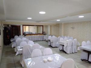 a banquet hall with white chairs and tables and tablesktop at Altamira Hotel in Karakol