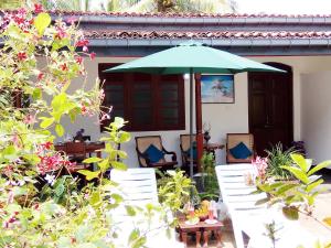 patio z zielonym parasolem, krzesłami i stołami w obiekcie Walauwa The Villa Ahungalla w mieście Ahungalla
