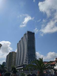 een hoog gebouw met een palmboom ervoor bij Orbi Residence Apartment in Batoemi