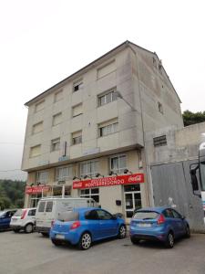 un edificio con coches estacionados frente a él en Pensión Monterredondo, en Meira