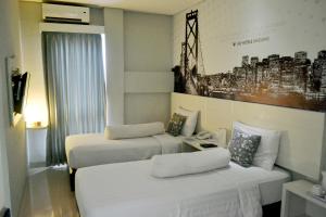 Habitación de hotel con 2 camas y una foto en la pared en Vio Cihampelas, en Bandung