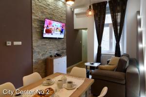 een woonkamer met een tafel en een tv aan een bakstenen muur bij Apartments City Center in Zagreb
