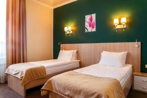 2 camas en una habitación de hotel con paredes verdes en AYKUN Hotel by AG Hotels Group en Astaná