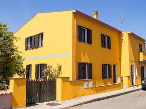 ein gelbes Haus mit schwarzen Fenstern und einem Zaun in der Unterkunft Casa Vacanza Valledoria in Valledoria
