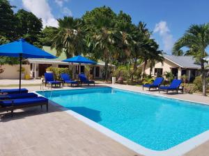 una piscina con sedie e ombrelloni blu di Villas de Mer a Grand'Anse Praslin