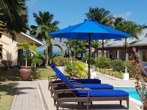 un gruppo di sedie a sdraio con ombrellone accanto alla piscina di Villas de Mer a Grand'Anse Praslin