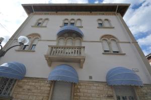 - un bâtiment avec des fenêtres bleues et un balcon dans l'établissement Les 7 Suites Erica, à Grado
