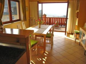 a kitchen with a wooden table with chairs and a balcony at Ferienwohnung-BergIdylle-bei-Hotel-BERGHOF in Lichtenhain