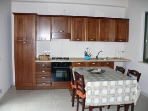 a kitchen with wooden cabinets and a table with chairs at B&B La Vecchia Stazione in Gioiosa Ionica