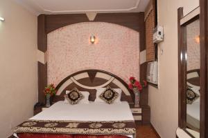
a bedroom with a bed, a dresser and a lamp at Hotel Yatri International in New Delhi
