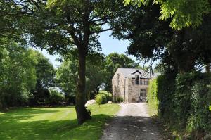 a dirt road leading to a large stone house at The Barn at Cae Bach in Gwalchmai
