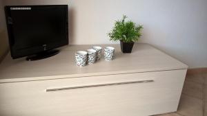 a dresser with three cups and a television on it at Residence Eolo in Porto Pozzo